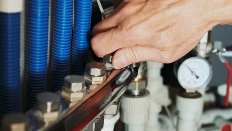 fontanero profesional. servicio de reparación de tuberías. reparador arreglando un calentador de agua de gas con un destornillador. manos de trabajador arreglando el sistema de calefacción