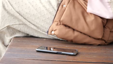 a black smartphone lies on a wooden table