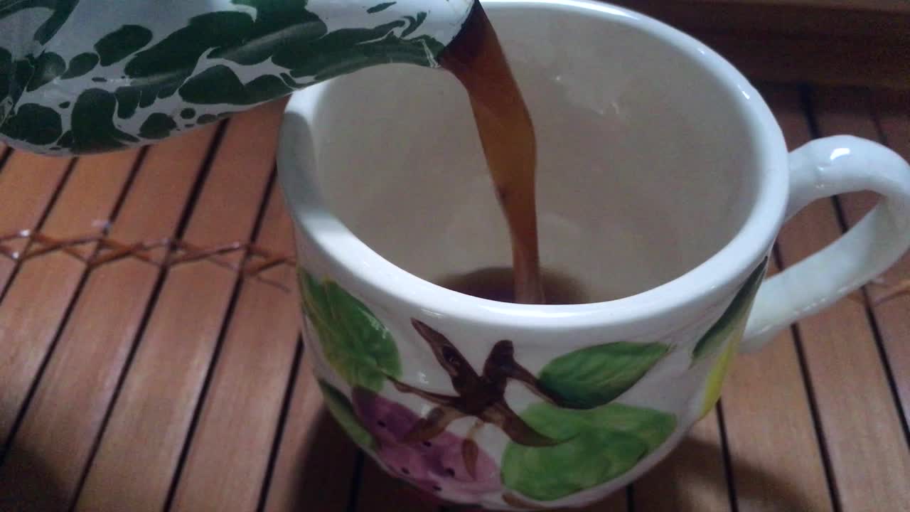 vertiendo café negro en una taza de crema de una tetera de esmalte