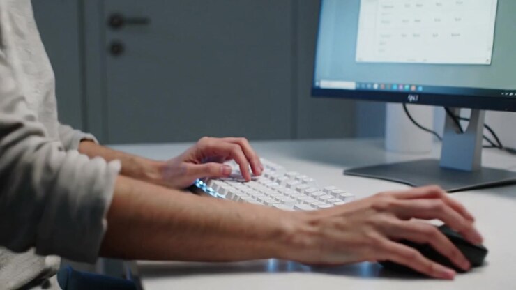 Typing user in long-sleeve top switching from keyboard red keycap to mouse at desk editing grid
