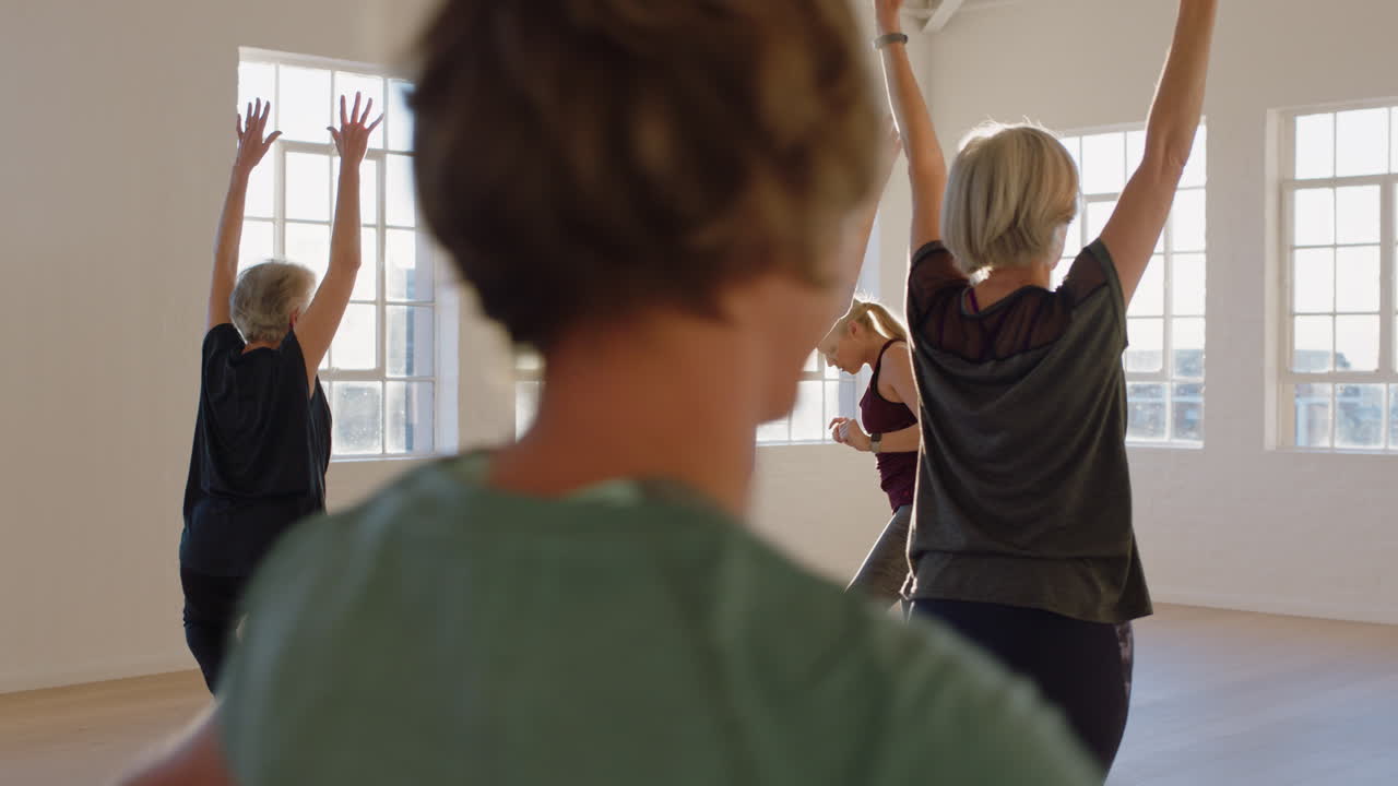 istruttore di lezione di yoga che insegna alle donne mature che praticano la posa di montagna godendo di uno stile di vita sano nella sala fitness all'alba