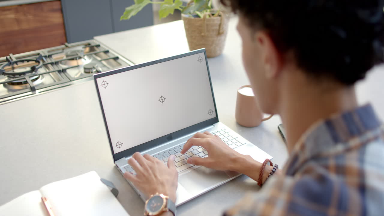 Typing on laptop, teenage boy working from home at kitchen counter, copy space