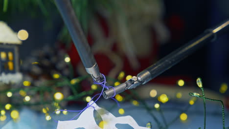 tiny forceps of da vinci system tying a knot on a thread. fastening the thread on the paper snowflake by robotic arms of da vinci surgical system. close up.