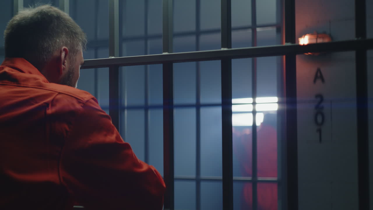 cara de cerca de un anciano prisionero enojado de pie detrás de barras de metal (imágenes de stock)