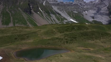 Beautiful-grassy-meadow-surrounded-by-mountain-cliffs-in-the-French-Alps