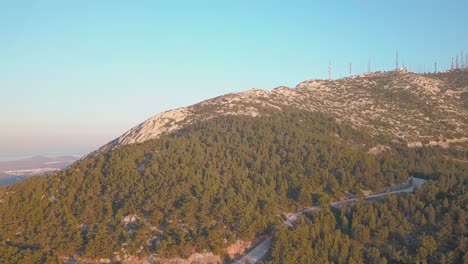 forward aerial shot of mountain ymittos in athens, showing an array of antennas during golden hour