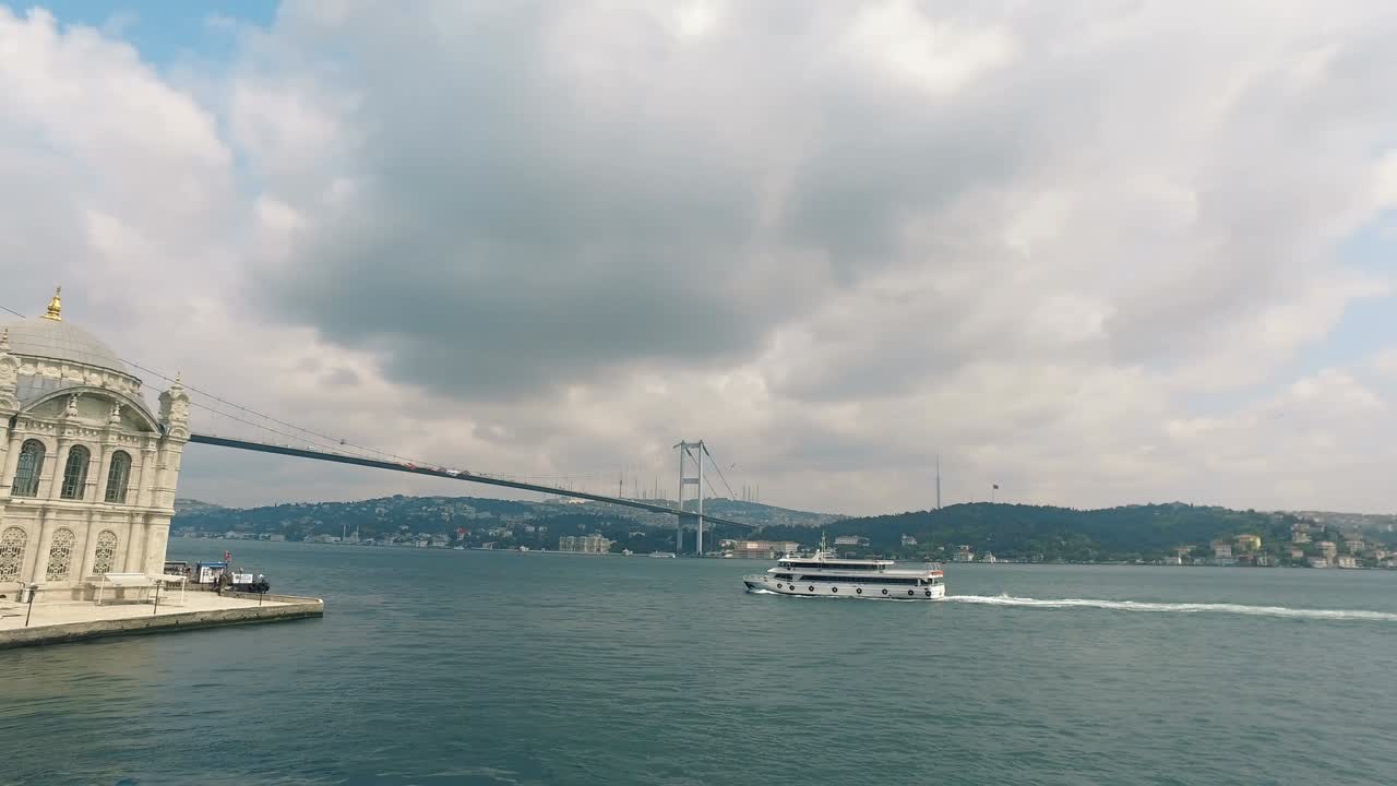 Tourist Boat under Bosporus Bridge with view of Ortakoy Mosque