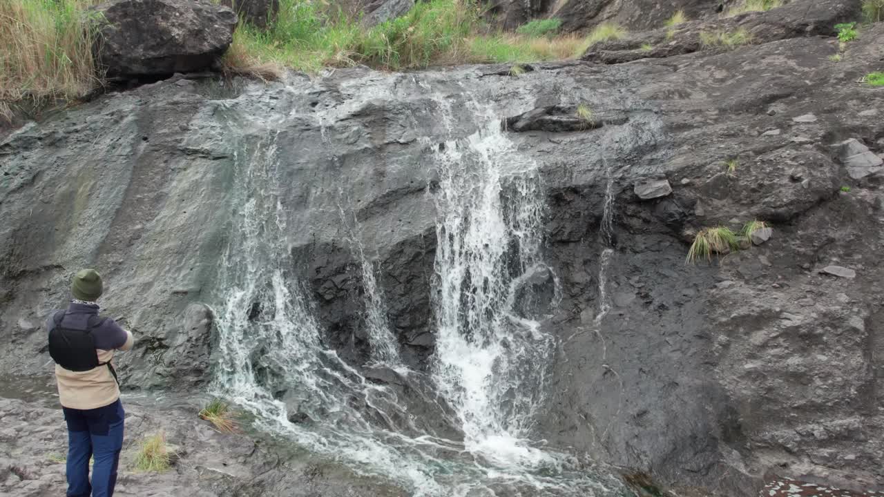 Un explorador de pie cerca de una cascada torrencial en el precioso barranco de El Risco, Gran Canaria