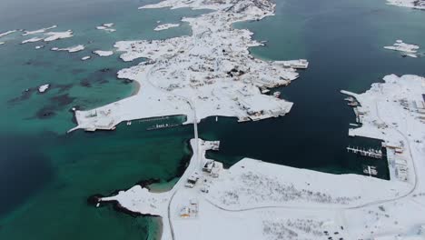 Drone-view-in-Tromso-area-in-winter-flying-over-a-snowy-flat-islands-connected-by-bridges-with-small-towns-in-Norway-with-white-mountains-in-the-horizon