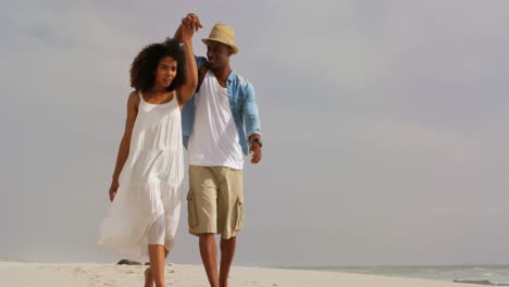 front view of african american couple walking hand in hand on the beach 4k