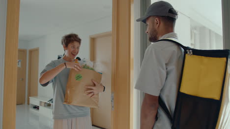 delivery guy bringing groceries to young woman at home