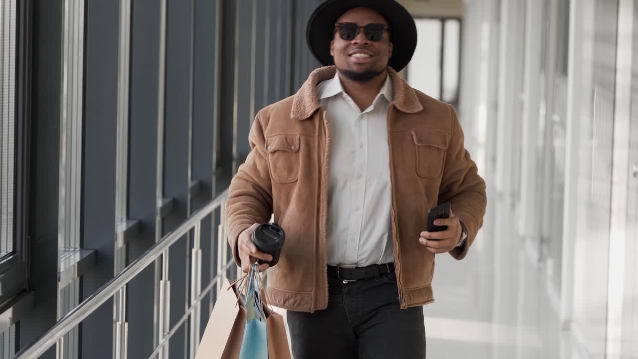 jolie afro-américaine marchant dans le couloir dansant avec des sacs à provisions au centre commercial