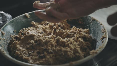 baker's hand rolling and shaping cookie batter