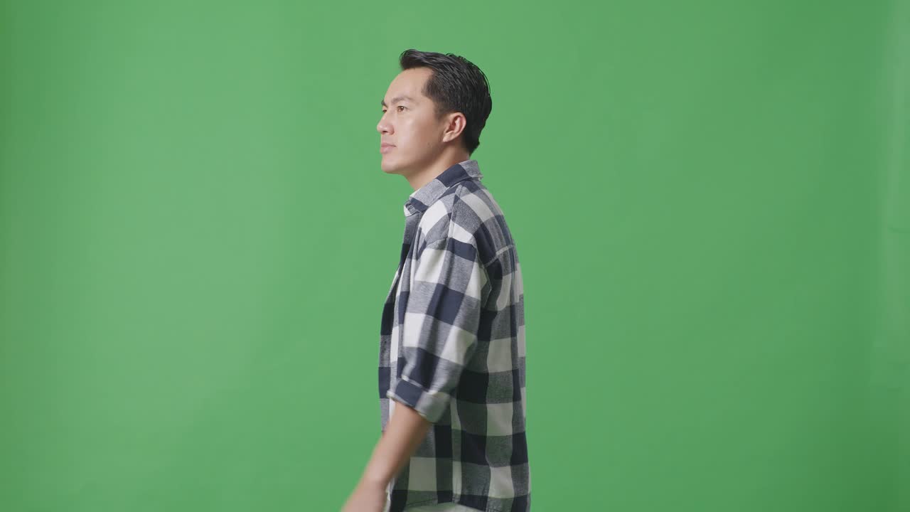 Side View Of Asian Man Walking And Looking Around In Green Screen Background