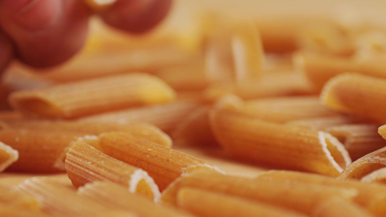 Pasta integrale biologica, maccheroni di semola di grano duro, penne rigate crude in una ciotola di legno. Filmato 4k di alta qualità