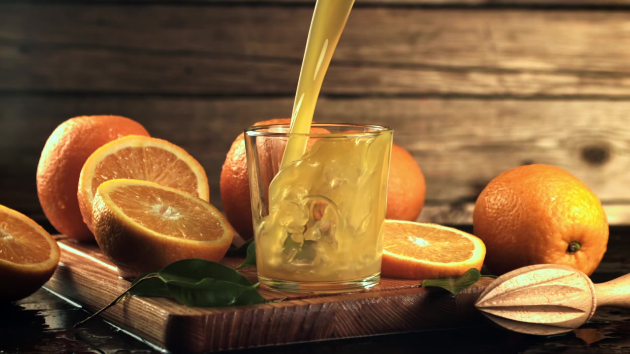 Succo d'arancia fresco che si versa in un bicchiere con arance