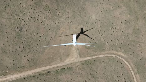 disparo de arriba hacia abajo de la turbina eólica girando y arrojando sombra y suelo desértico de arena