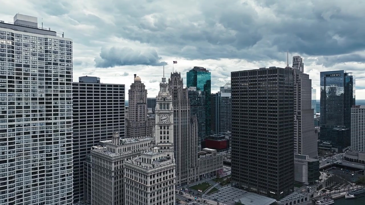 Orbita aerea a sinistra attorno a una torre dell'orologio con Chicago illuminata dalla luce del sole e grattacieli che svettano sopra il fiume.