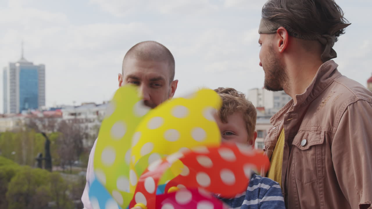Cute Boy with Gay Fathers Playing with Pinwheel Toy