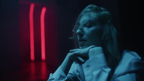 woman sitting in dark room with neon lights
