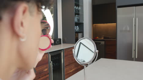 applying makeup, person using compact mirror and brush in modern kitchen