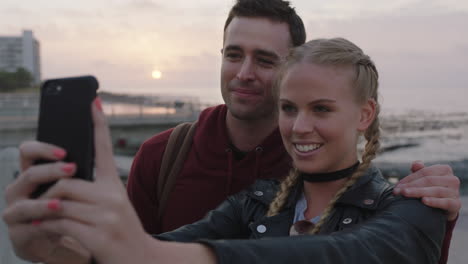 happy young couple posing for selfie photo using phone enjoying seaside sunset