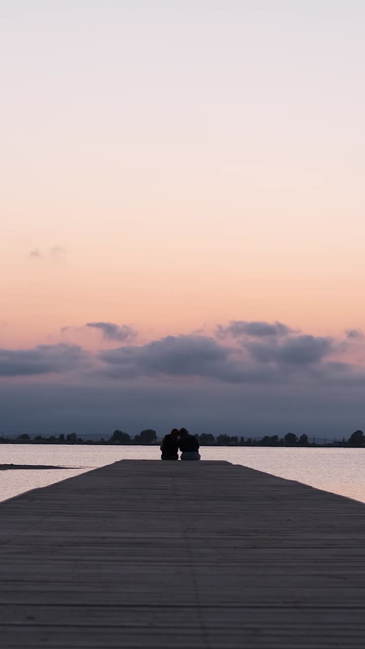 Anonymous persons sitting on end of pier