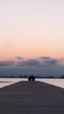 anonymous persons sitting on end of pier
