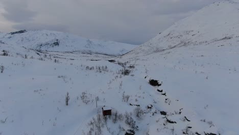 Drone-view-in-Tromso-area-in-winter-flying-over-a-snowy-landscape-and-white-and-rocky-mountains-in-Norway