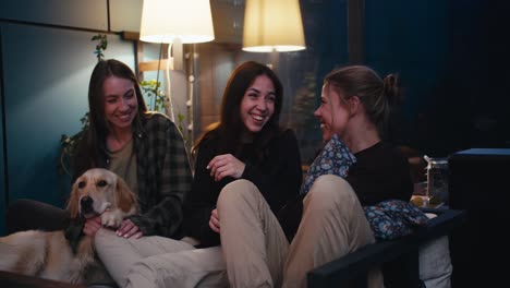 Happy-trio-of-girls-are-sitting-on-the-couch-chatting-and-having-fun.-Active-communication,-cheerful-and-cozy-evening