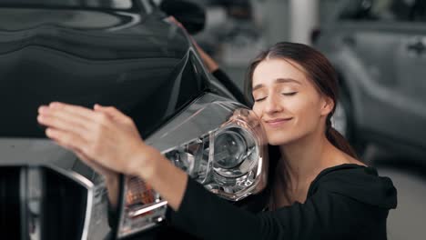 Close-up-of-a-beautiful-happy-girl-who-hugs-a-new-car-and-kisses