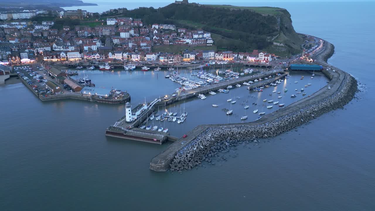 영국 스카버러에서 해가 지는 동안 바다에서 배와 함께 스카버루 항구의 공중 후방