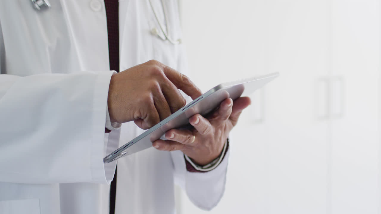 video de la sección media de un médico biracial usando una tableta