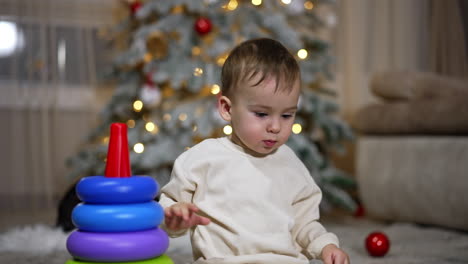 baby playing with stacking rings near christmas tree