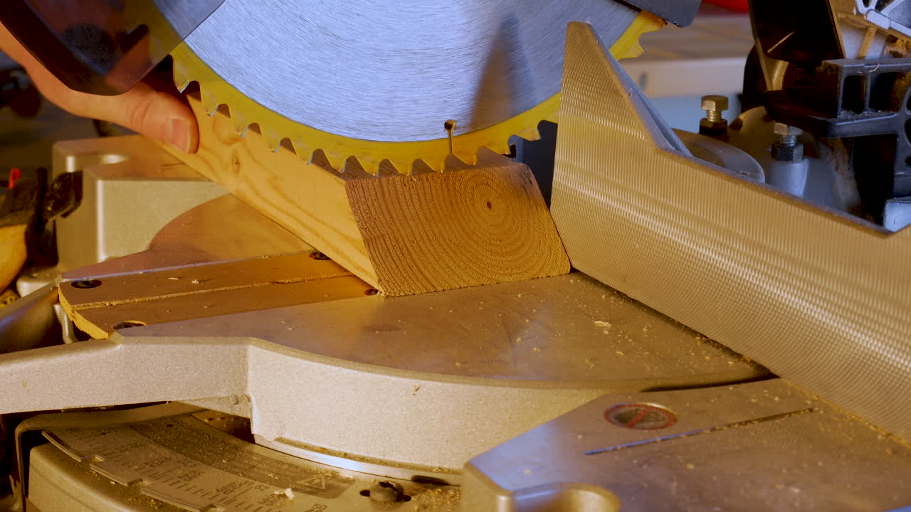 usando una sierra para cortar ingletes para cortar un tablón de madera 2x4 - cerrar