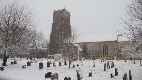 tracking past old english church on very cold snowing day