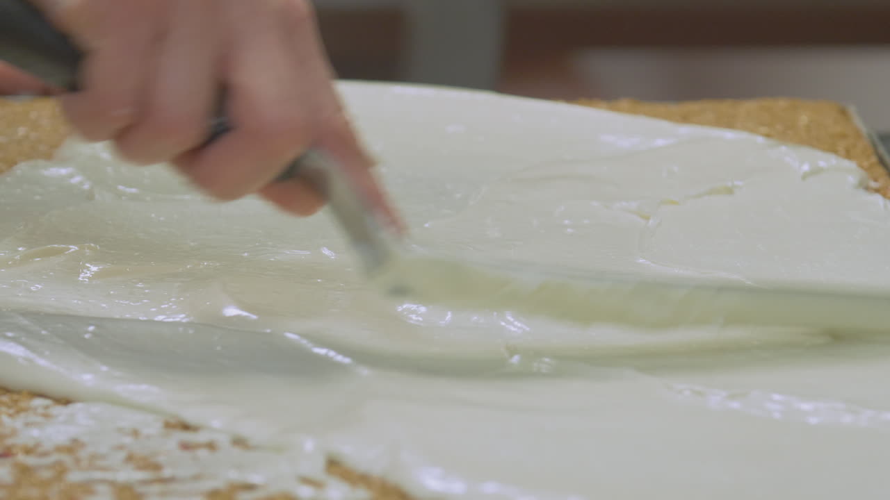 Icing mix is spread across the top of a flapjack or oat slice. Factory scale