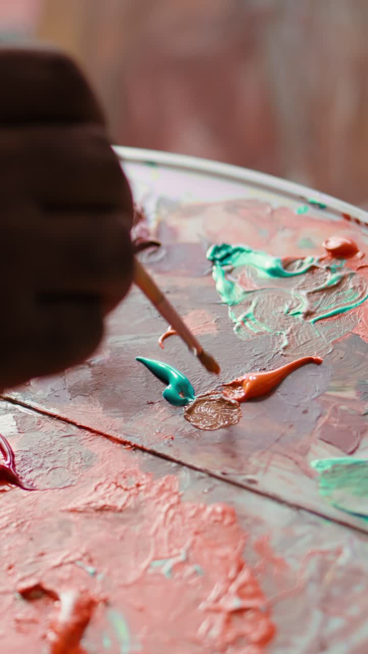 Artist's Hand Mixing Vibrant Colors on a Paint Palette