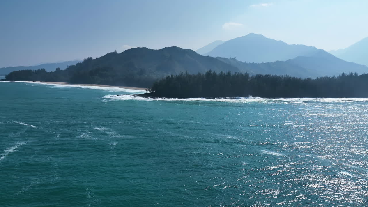 Aerial view of large waves hitting the coastline of Kauai, Hawaii, sunny day