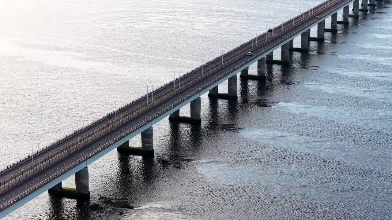 Aerial view of car crossing Tay Road Bridge over calm water in soft daylight
