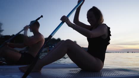 a couple paddleboarding during a serene dusk
