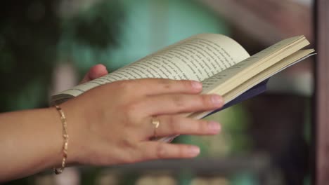 a woman’s hands flipping through a book while reading. ideal for concepts like learning, relaxation, or quiet moments.