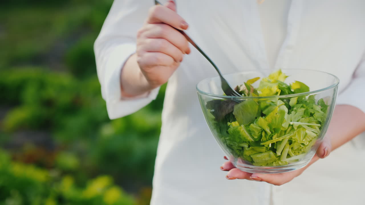 여자가 자라는 침대 근처에서 샐러드를 먹습니다.