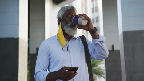 Afroamerikanischer-älterer-Mann,-Der-Im-Firmenpark-Kaffee-Trinkt-Und-Sein-Smartphone-Benutzt