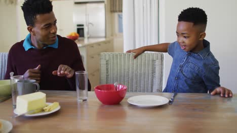 Afroamerikanischer-Junge-Sitzt-Mit-Seiner-Familie-Am-Esstisch,-Um-Zu-Hause-Gemeinsam-Zu-Frühstücken