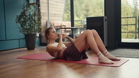 A-blonde-girl-in-a-white-top-does-exercises-to-strengthen-the-abdominal-muscles-in-an-industrial-country-house.-Fitness-at-home