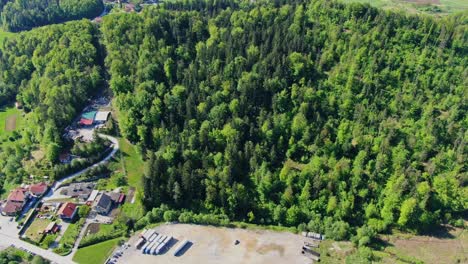 Aerial-view-over-the-tall-dense-green-trees-around-the-human-settlement-in-Velenje-city,-Slovenia