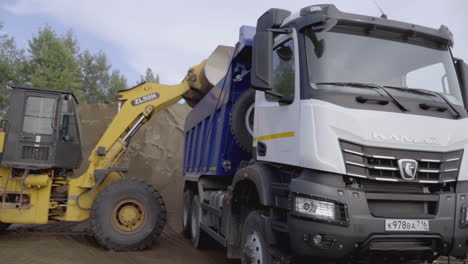 excavator loading sand onto a dump truck