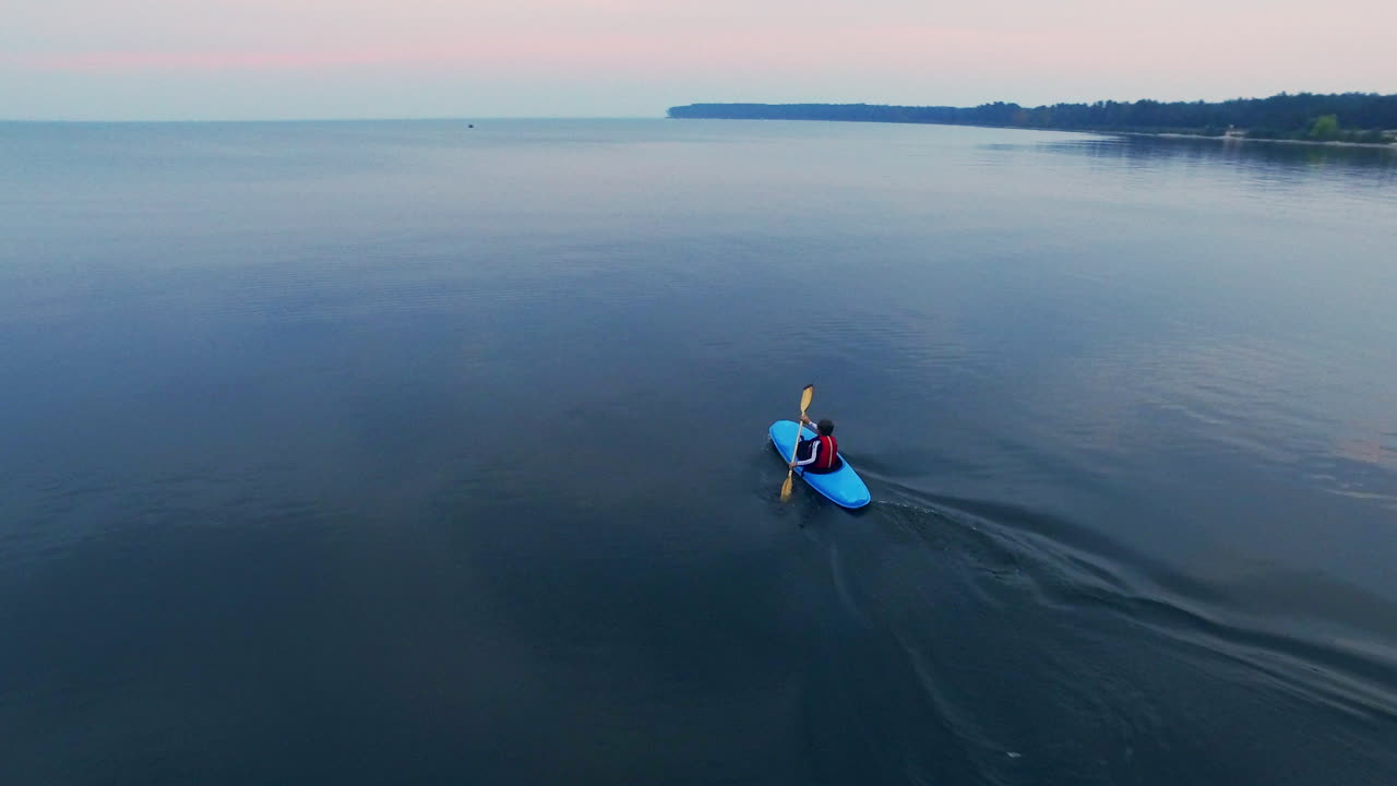 평온 한 호수 에서 카야크 를 타는 젊은 남자