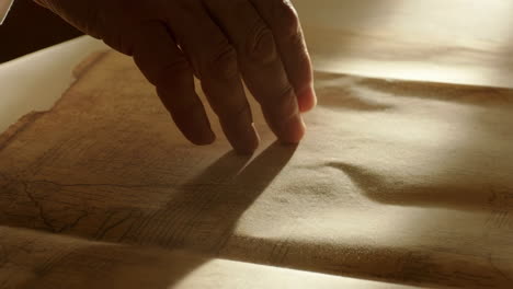 hand examining an ancient document under light